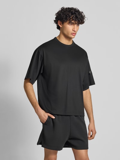 Männermodel trägt Relaxed Fit T-Shirt aus reiner Baumwolle von adidas Sportswear, Optik: Unifarben, Ganzkörperansicht von vorne.