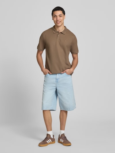 Model męski nosi koszulkę polo Regular Fit Poloshirt mit Strukturmuster Modell 'AUSTIN' von Jack & Jones, mieszanka bawełny, fakturowany wzór, haft, listwa guzikowa, kolor brązowy, długość tyłu w rozmiarze M: 69 cm, pełny widok z przodu.