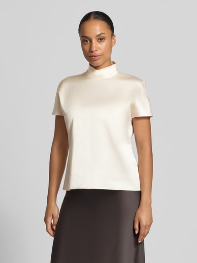 Frauenmodel trägt T-Shirt aus Viskose-Mix mit Stehkragen von Stefanel, satinartige creme Farbe, lockere Passform, Nahaufnahme Oberkörper.