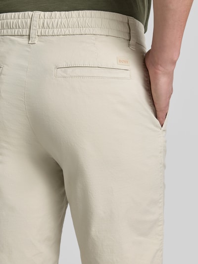 Männermodel trägt Tapered Chinoshorts aus Baumwoll-Mix Modell 'CHINO_TAPERED_DS_3S' von BOSS Orange, Optik: Unifarben, Nahaufnahme Rückansicht.