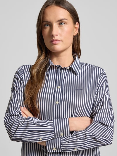 Frauenmodel trägt Hemdbluse aus Baumwolle mit Streifenmuster von GANT, gerader Schnitt, Hemdblusenkragen, Label-Detail, Langärmelig, Nahaufnahme Oberkörper.