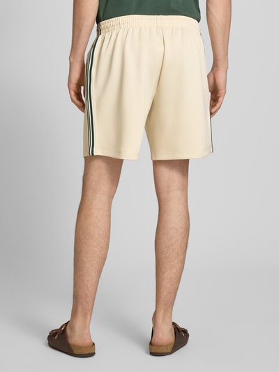 Männermodel trägt Regular Fit Sweatshorts mit elastischem Bund Modell 'RIBER' von Only & Sons, unifarben mit Kontraststreifen, Ganzkörperansicht Rückansicht.