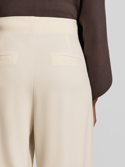 Frauenmodel trägt Relaxed Fit Anzughose mit Bundfalten Modell 'SC-SIHAM 103' von Soyaconcept in Creme, glatte Textur, Nahaufnahme Rückansicht, Damen Anzughose von Soyaconcept.