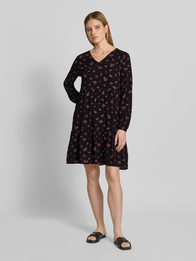 Frauenmodel trägt Minikleid aus Viskose mit V-Ausschnitt von Zero, taillierter Schnitt, schwarz mit rosa Blumen, Ganzkörperansicht von vorne, reine Viskose, elastische Ärmelabschlüsse, Rückenlänge bei Größe 36: 80 cm, Brustweite: 39 cm, Ärmellänge: 60 cm.
