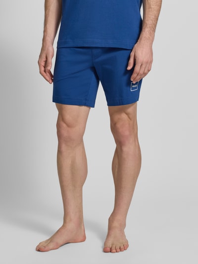Männermodel trägt Regular Fit Sweatshorts aus Baumwoll-Mix Modell 'LAZE SHORTS CW' von HUGO, Optik: Unifarben, Label-Print, Bundabschluss: Elastisch; Nahaufnahme Unterkörper.