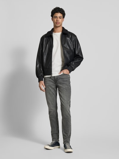 Männermodel trägt Regular Fit Jacke in Leder-Optik mit Umlegekragen von Calvin Klein Jeans, Schwarz, Logo-Detail, Eingrifftaschen, Ganzkörperansicht von vorne. Rückenlänge bei Größe M 64 cm, Schulterbreite 51 cm, Brustweite 62 cm, Ärmellänge 63 cm, Zweiwege-Reißverschluss, elastische Abschlüsse.