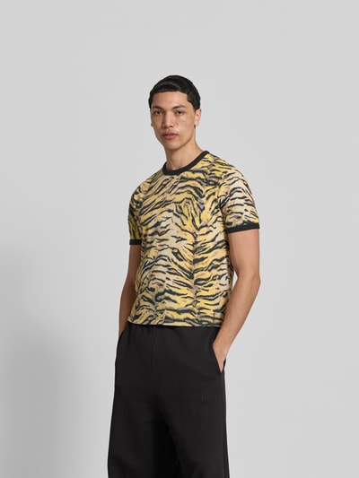Männermodel trägt T-Shirt mit Allover-Animal-Print von Kenzo, gelb-schwarze Farbkombination, Reine Baumwolle, Slim-Fit, Rundhalsausschnitt, Kurzärmelig, Rückenlänge 61 cm bei Größe M, Ganzkörperansicht von vorne.