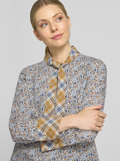 Kobiece model prezentuje bluzkę z wiązaniem pod szyją 'Schluppenbluse im Allover-Look' od Emily Van den Bergh, bawełna, krój regular fit, wzór na całej powierzchni, listwa guzikowa, długość tyłu w rozmiarze 36: 63 cm, długość rękawów w rozmiarze 36: 62 cm, zbliżenie na górną część ciała.