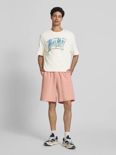 Männermodel trägt Herren T-Shirt mit Label-Print Modell 'Sport Gradient' von KARL KANI, Reine Baumwolle, Boxy-Fit, Weiß, Ganzkörperansicht von vorne. Rückenlänge in Größe M beträgt 68 cm, gerippter Rundhalsausschnitt.