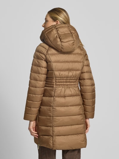 Frauenmodel trägt Steppmantel mit Reißverschlusstaschen und Kapuze von MICHAEL Michael Kors in Hellbraun, gesteppt, Ganzkörperansicht Rückansicht. Gerader Schnitt, Kapuze mit Tunnelzug und Kordelstoppern, Reißverschluss, seitliche Reißverschlusstaschen und seitliche Reißverschlüsse am Saum. Rückenlänge ca. 87 cm, Schulterbreite 45 cm, Brustweite 52 cm, Ärmellänge 59 cm.
