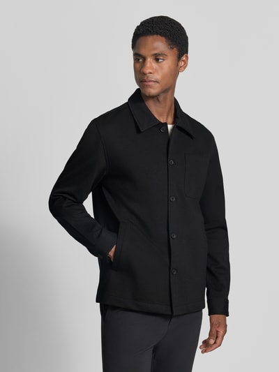 Männermodel trägt Slim Fit Hemdjacke mit Viskose-Anteil von Lindbergh in Schwarz mit Umlegekragen und Brusttasche, Ganzkörperansicht von vorne. Elastischer Material-Mix, glatte Struktur, Produktlänge 70 cm bei Größe M.