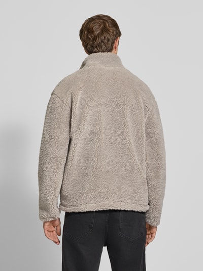 Männermodel trägt Fleecejacke mit Label-Detail und Reißverschluss von REVIEW in Beige, Teddyfellstruktur, Ganzkörperansicht Rückansicht. Regular Fit, Stehkragen, Rückenlänge 70 cm, Schulterbreite 56 cm, Brustweite 59 cm, Ärmellänge 64 cm.