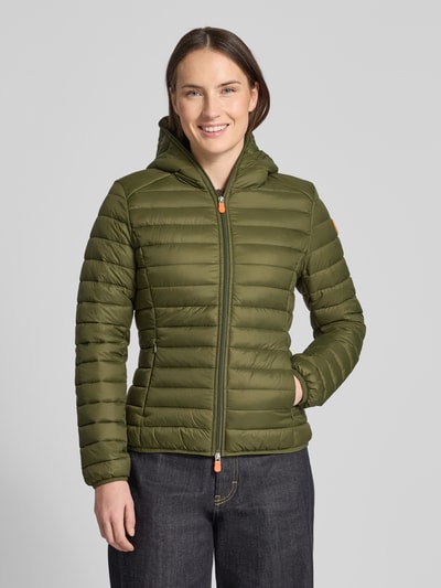 Frauenmodel trägt olivgrüne Steppjacke mit Kapuze Modell 'DAISY' von SAVE THE DUCK, körpernah geschnitten, glatte Textur, Ganzkörperansicht von vorne.