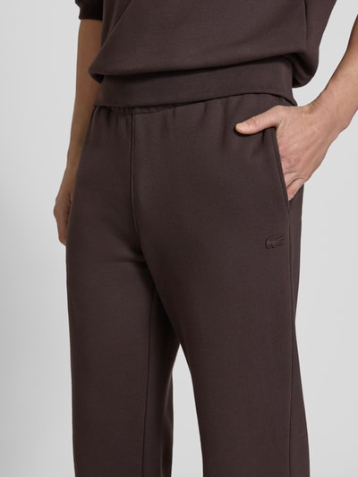 Männermodel trägt Loose Fit Sweatpants aus reiner Baumwolle von Lacoste in Optik: Unifarben mit Logo-Detail, Nahaufnahme Oberkörper.