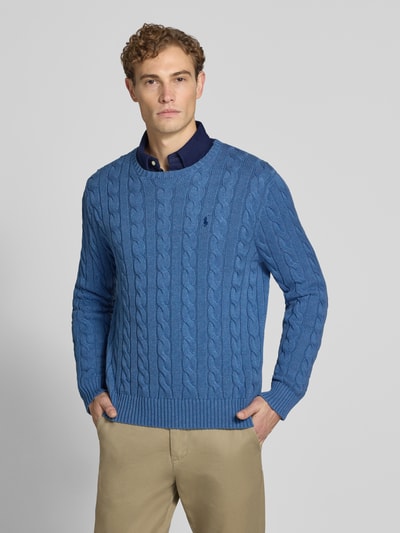 Männermodel trägt Regular Fit Pullover aus reiner Baumwolle von Polo Ralph Lauren in Blau mit Zopfstrickmuster, Ganzkörperansicht von vorne.