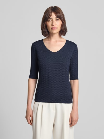 Frauenmodel trägt Regular Fit Bluse mit Strukturmuster von Emporio Armani in Dunkelblau, V-Ausschnitt, Halbarm, elastischer Material-Mix, Ganzkörperansicht von vorne.