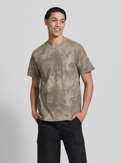 Männermodel trägt T-Shirt aus Baumwolle mit Rundhalsausschnitt von G-Star Raw in Beige mit Allover-Look, Regular Fit, Ganzkörperansicht von vorne.