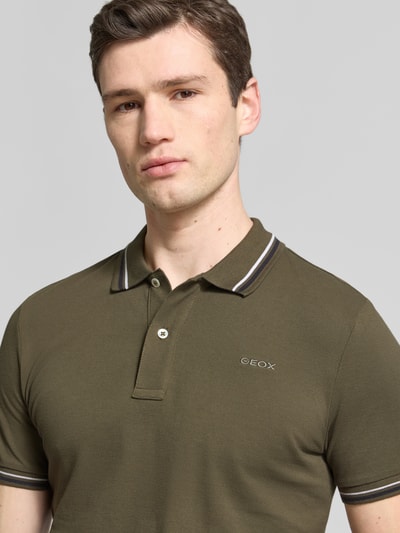 Mężczyzna nosi Slim Fit Poloshirt mit Kontraststreifen od Geox, mieszanka bawełny, kołnierzyk polo, listwa guzikowa, paski w kontrastowym kolorze, długość tyłu w rozmiarze M: 69 cm, zbliżenie górnej części ciała.