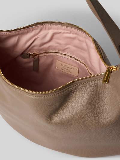 Produktfoto, Shoulder Bag mit Logo-Print Modell 'Thess' von Coccinelle aus beigem Leder, rosafarbenes Innenfutter, Reißverschluss, Detailaufnahme, Damen Shoulder Bag von Coccinelle, Hauptfach mit Reißverschluss, Trageriemen mit Tunnelzug, Größe 1: 40x31x6 cm, Schulterriemen 50 cm