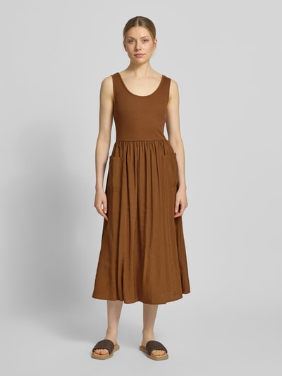 Frauenmodel trägt Midikleid mit aufgesetzten Taschen von Rich & Royal aus Micromodal-Mix in Braun, taillierte Passform, Rundhalsausschnitt, Ärmelloses-Design, Rücklänge bei Größe S 114 cm, Brustweite 32 cm, Ganzkörperansicht von vorne.