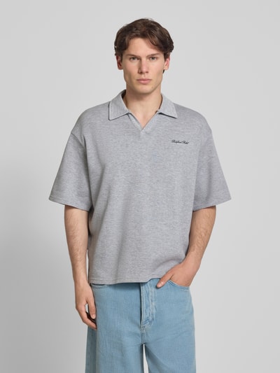 Männermodel trägt Regular Fit Poloshirt mit Logo Modell 'Eddie' von Redefined Rebel aus Baumwoll-Mix in Grau, V-Ausschnitt, Ganzkörperansicht von vorne. Herren Poloshirt, Rückenlänge bei Größe M: 73 cm.