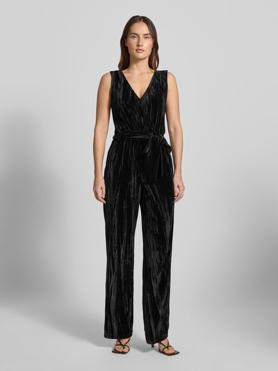 Frauenmodel trägt Regular Fit Jumpsuit aus Samt von Tom Tailor Denim in Schwarz mit V-Ausschnitt und Bindegürtel, Ganzkörperansicht von vorne.
