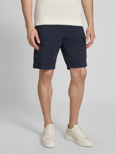 Männermodel trägt Relaxed Fit Cargoshorts aus Baumwoll-Mix Modell 'SISLA' von BOSS Orange in Dunkelblau, unifarben, mit Label Patch, Knopfverschluss und mehreren Taschen, Baumwollstruktur, Ganzkörperansicht von vorne.