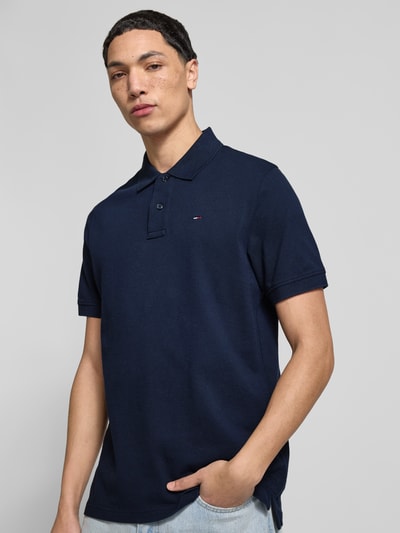 Mężczyznamodel nosi Regular Fit Poloshirt aus reiner Baumwolle von Tommy Jeans, efekt: jednolity kolor, krój regular fit, wyhaftowane logo, kołnierzyk polo, krótki rękaw, wykończenie: z bocznymi rozcięciami, wykończenie materiału: pika, bawełna, całkowity widok z przodu.