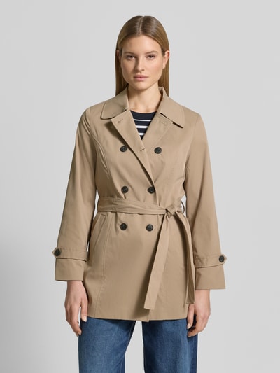 Vrouwenmodel draagt Regular Fit Trenchcoat met tailleriempje om te strikken model 'CHALSEA OLIVIA' van Vero Moda, unicolor twill, dubbele knopenrij, steekzakken, beige, voorkant volledig zichtbaar, vooraanzicht busteshot.