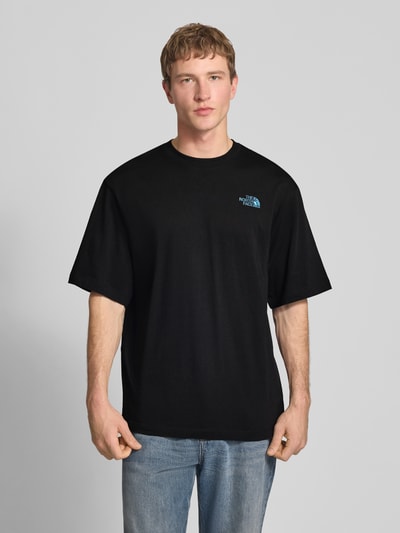 Männermodel trägt Oversized T-Shirt mit Logo und Rundhalsausschnitt von The North Face in Schwarz aus Reine Baumwolle, Ganzkörperansicht von vorne. Herren T-Shirt, oversized, Logo, Rückenlänge bei Größe M: 73 cm.