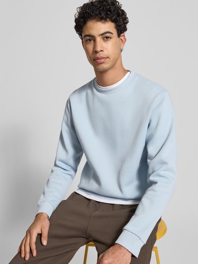 Mężczyznamodel nosi Sweatshirt mit gerippten Abschlüssen Modell 'BRADLEY' von Jack & Jones, bawełniany materiał-mix, krój regular fit, jasnoniebieski kolor, okrągły dekolt, prążkowane wykończenia, długość tyłu w rozmiarze M: 67 cm, długość rękawa: 65 cm, ujęcie z przodu – zbliżenie na górną część ciała.