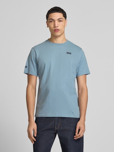 Männermodel trägt T-Shirt mit Logo- und Motiv-Print Modell 'SHORELINE' von Helly Hansen in Blau, Reine Baumwolle, Gerader-Schnitt, Rundhalsausschnitt, Rückenlänge bei Größe M 70 cm, Ganzkörperansicht von vorne.