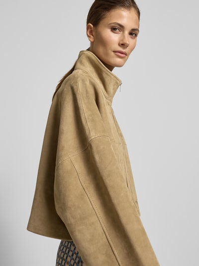 Frauenmodel trägt Relaxed Fit Lederjacke mit Stehkragen von Drykorn im Leder-Mix mit aufgesetzten Eingrifftaschen und Reißverschluss, Nahaufnahme Oberkörper.