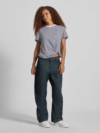 Frauenmodel trägt Relaxed Fit T-Shirt aus reiner Baumwolle mit geknotetem Saum von G-Star RAW, feine Streifen, kombiniert mit weiter Jeans, Ganzkörperansicht von vorne.