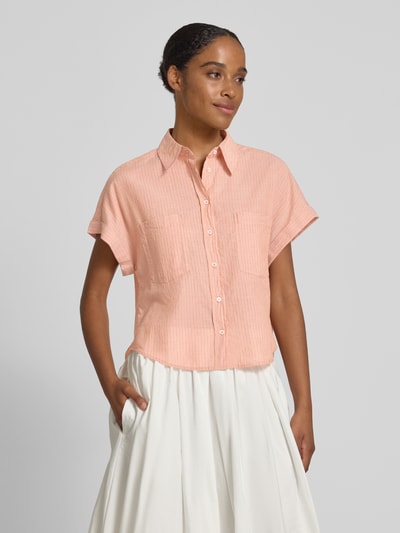 Frauenmodel trägt Boxy Fit Hemdbluse aus reiner Baumwolle von Marc O'Polo, Optik:Allover-Muster, gestreift, Passform: Boxy-Fit, Hemdkragen, Brusttaschen, Rückenpasse mit Raffung, Kurzarm mit fixiertem Umschlag, Material: Reine Baumwolle, Farben: zartes Orange und Weiß, Textur: weich, feine Streifen, Ganzkörperansicht von vorne.