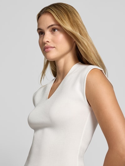 Frauenmodel trägt Stricktop mit V-Ausschnitt Modell 'CANELONS' von MANGO, weiß, taillierter Schnitt, feinstrukturiert, Nahaufnahme Oberkörper, Viskose-Mix.