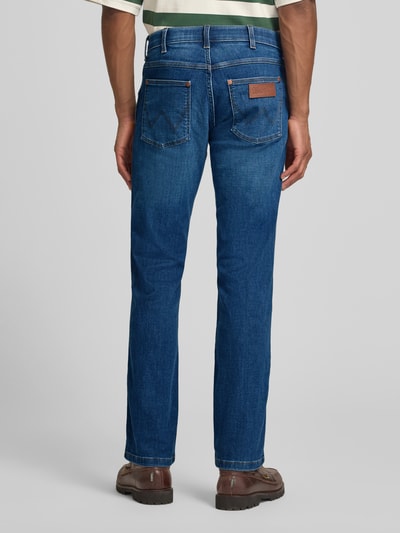 Männermodel trägt Straight Fit Jeans im 5-Pocket-Design Modell 'Greensboro' von Wrangler, Baumwoll-Mix mit Stretch-Anteil, Gerader-Schnitt, mittleres Blau, Bundweite 42 cm, Innenbeinlänge 79 cm, Knopf-Reißverschluss, Jeans-Textur, Ganzkörperansicht Rückansicht.