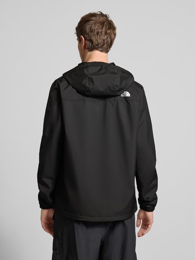 Mężczyzna nosi kurtkę z kapturem z tunelem, model 'ANTORA' od The North Face, krój regular fit, logo, czarny kolor, długość tyłu 74 cm, szerokość ramion 46 cm, szerokość w rozmiarze M 58 cm, długość rękawów 69 cm, zamek błyskawiczny, całkowity widok z tyłu.