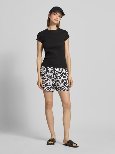 Frauenmodel trägt Regular Fit Shorts aus reiner Viskose Modell 'BARRI' von Pieces mit Optik:Allover-Muster und floralem Muster, Ganzkörperansicht von vorne.