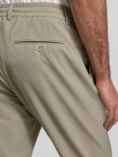 Mężczyzna nosi Slim Fit Stoffhose mit Strukturmuster von CRUNA, elastyczna mieszanka materiałów, fakturowany wzór, kieszenie z tyłu i wpuszczane, elastyczny pas, szerokość w rozmiarze 50: 44 cm, długość wewnętrzna nogawki w rozmiarze 50: 79 cm, kolor beżowy, detal tylnej części, zbliżenie na pośladek.