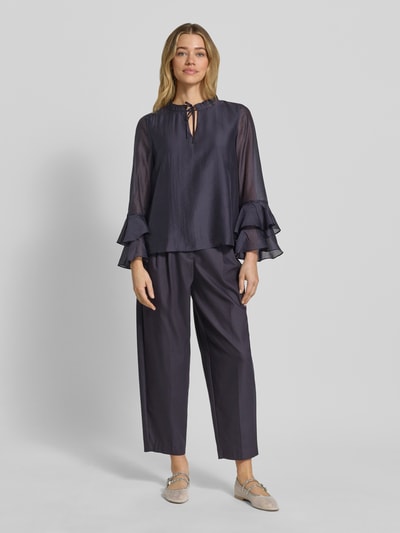 Frauenmodel trägt Regular Fit Bluse aus Lyocell-Mix mit Volants von Comma in dunklem Blau, Schlüsselloch-Ausschnitt, fließende Struktur, Rückenlänge bei Größe 36: 58 cm, Ärmellänge 60 cm, Ganzkörperansicht von vorne.