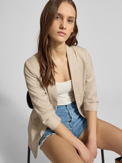 Frauenmodel trägt Regular Fit Longblazer mit 3/4-Ärmeln Modell 'ELLY' von ONLY in Melange-Optik, Schalkragen, ohne Verschluss, angedeutete Paspeltaschen, beige Textur, Nahaufnahme Oberkörper.