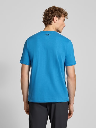 Männermodel trägt Regular Fit Sport-T-Shirt aus Baumwoll-Mix von Under Armour in Blau, schwarze Hose, Ganzkörperansicht Rückansicht.
