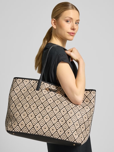 Kobiece modelka nosi Tote Bag mit herausnehmbarer Tasche Modell 'Sophia' von Guess, beżowo-czarne geometryczne wzory, detal z logo, główna przegroda z zapięciem na magnes, smukły pasek na ramię, szerokość w rozmiarze 1: 47 cm, długość w rozmiarze 1: 34 cm, głębokość w rozmiarze 1: 20 cm, długość paska na ramię w rozmiarze 1: 59 cm, wyjmowana kieszeń zapinana na zamek błyskawiczny, ganzkörperansicht od frontu.