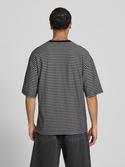 Männermodel trägt Herren T-Shirt mit feinen schwarzen und grauen Streifen, Produktname T-Shirt mit Logo-Stitching Modell 'Dupree' von Carhartt Work In Progress, Reine Baumwolle, Boxy-Fit, Rundhalsausschnitt, Rückenlänge bei Größe M 70 cm, Ganzkörperansicht Rückansicht.
