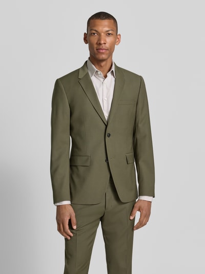 Männermodel trägt Sakko mit Woll-Anteil und Label-Patch Modell 'Jamie' von Tiger Of Sweden im Olivton, Material-Mix, Regular-Fit, Reverskragen, Knopfverschluss, Brustleistentasche, Pattentaschen; Rückenlänge 71 cm, Schulterbreite 41 cm, Ärmellänge 65 cm, Ganzkörperansicht von vorne.