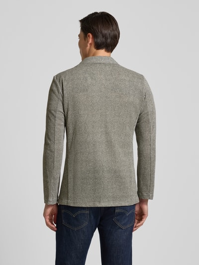 Męski model nosi Slim Fit 2-Knopf-Sakko mit Reverskragen von Zuitable, bawełniany mix ze stretchem, wzór strukturalny, krój slim fit, kieszenie naszywane, długość pleców w rozmiarze M: 74 cm, szerokość w rozmiarze M: 43 cm, długość rękawa w rozmiarze M: 65 cm, pełny widok sylwetki od tyłu.