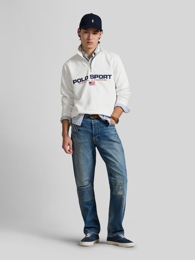 Männermodel trägt Relaxed Fit Troyer aus Baumwoll-Mix von Polo Ralph Lauren, unifarben weiß, Applikation Label Print, Ganzkörperansicht von vorne.