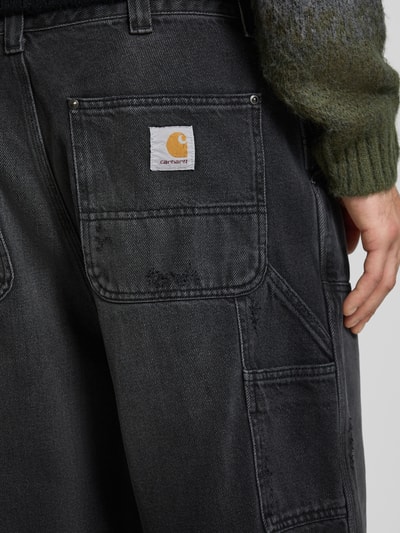 Männermodel trägt Wide Fit Jeans Logo-Patch Modell 'Grind' von Carhartt Work In Progress aus reiner Baumwolle, Detailaufnahme Rückansicht.