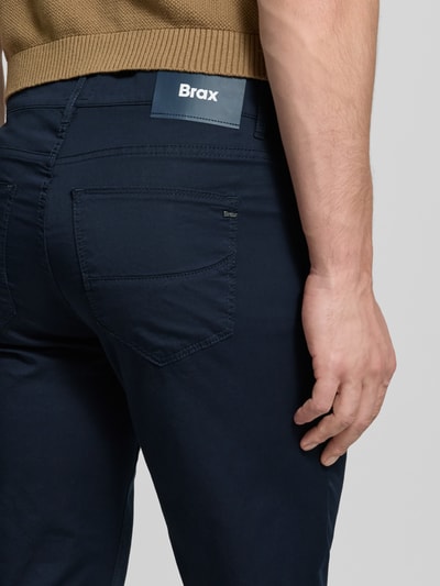 Męski model nosi Slim Fit Spodnie materiałowe z dodatkiem lyocellu Model 'Cadiz' od BRAX, 5 kieszeni, elastyczna mieszanka bawełny, zapięcie na guzik i zamek błyskawiczny, szerokość w rozmiarze 32/32: 107 cm, długość wewnętrzna nogawki: 81 cm, ujęcie: detal z tyłu.